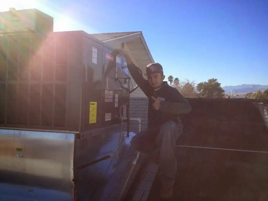 HVAC technician performing AC Tune-Up on a rooftop unit in Oskaloosa